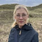 Woman in her 50s outdoors, looking at the camera, reflecting on her future and income after retirement